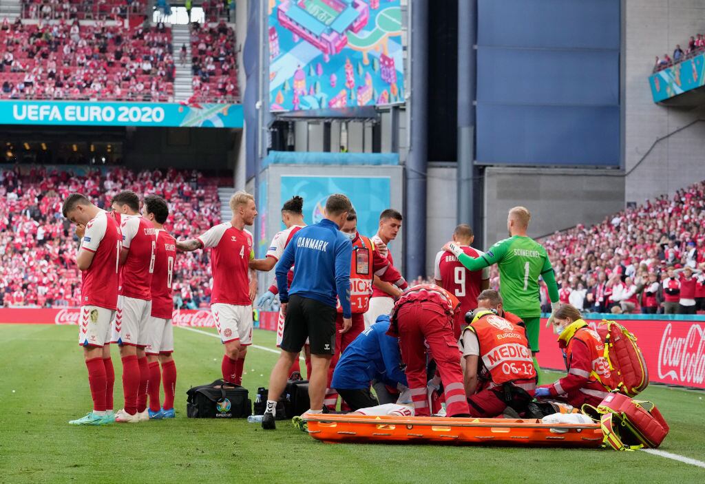 Jugadores se congregan al rededor de Eriksen, preocupados por su salud.
