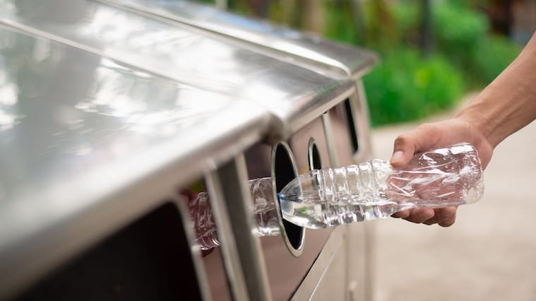 Man hand putting and putting plastic bottle waste iMto garbage trash,Close up hand throwing empty plastic bottle into the trash Recycling Concept.