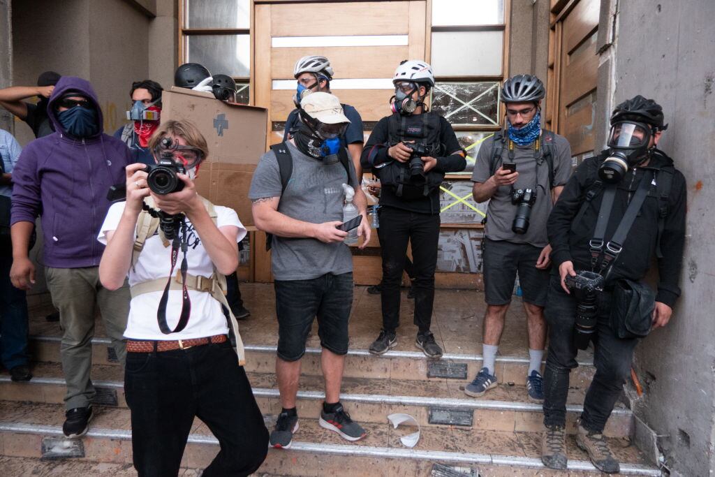 Reporteros trabajan protegidos durante las protestas en Santiago