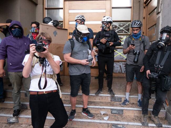 Reporteros trabajan protegidos durante las protestas en Santiago