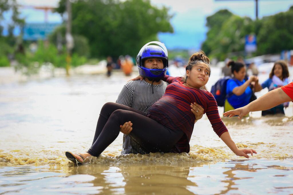 Un hombre traslada a una embarazada en medio de las inundaciones en Honduras