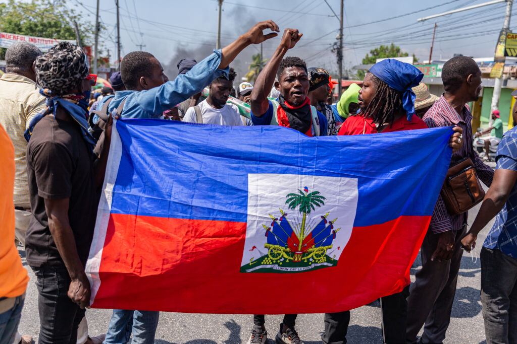 Un grupo de personas con la bandera de Haití en medio de las protestas contra el primer ministro Ariel Henry en la ciudad de Puerto Príncipe.