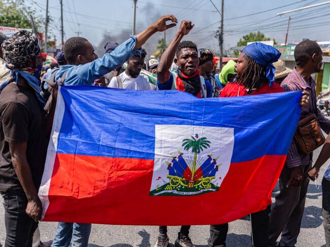 Un grupo de personas con la bandera de Haití en medio de las protestas contra el primer ministro Ariel Henry en la ciudad de Puerto Príncipe.