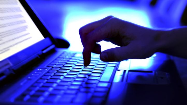 Close-up adult hand typing on laptop