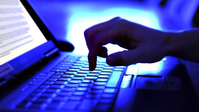 Close-up adult hand typing on laptop