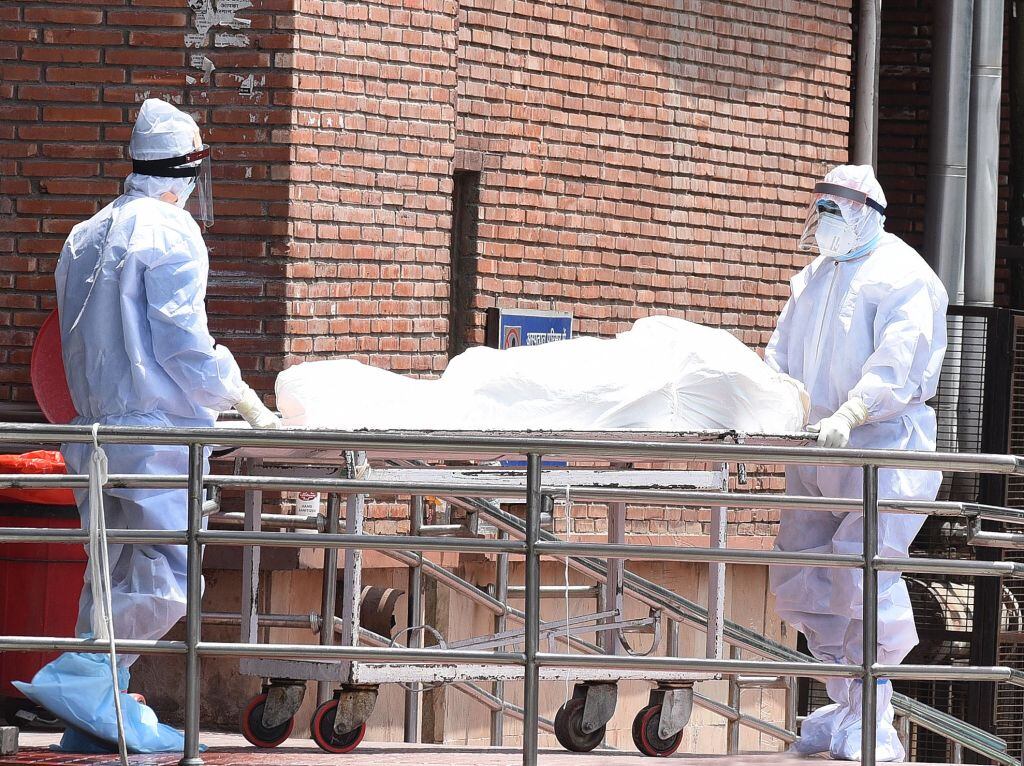 Trabajadores transportan a una víctima del Covid-19 en India