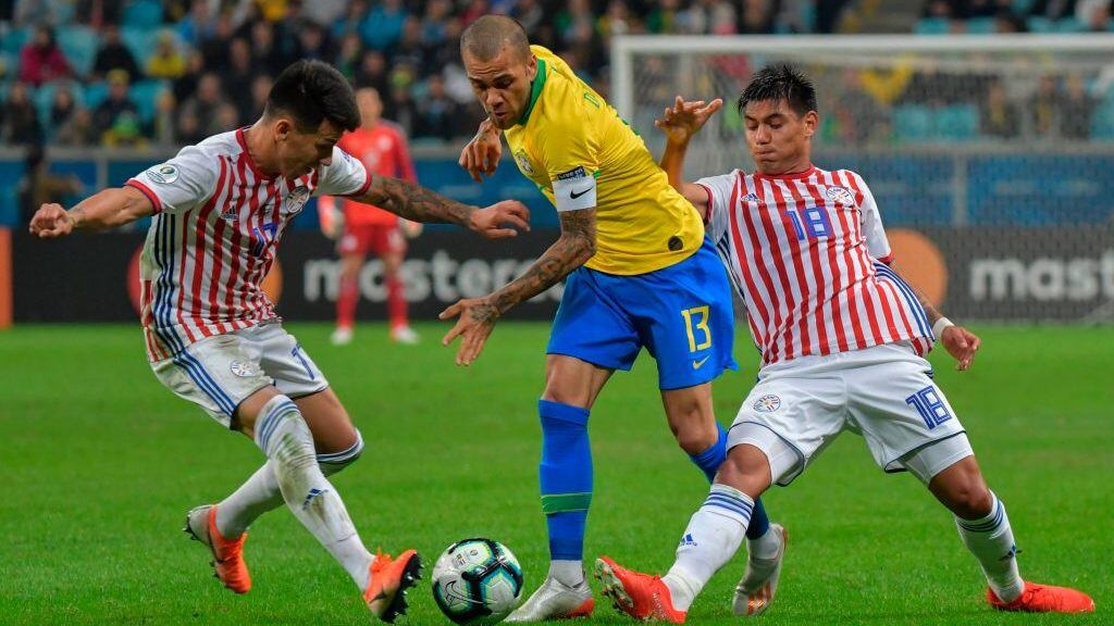 Brazil's Dani Alves (C) is marked by Paraguay's Hernan Perez (L) and Santiago Arzamendia during their Copa America football tournament quarter-final match at the Gremio Arena in Porto Alegre, Brazil, on June 27, 2019. (Photo by Luis ACOSTA / AFP)        (Photo credit should read LUIS ACOSTA/AFP via Getty Images)