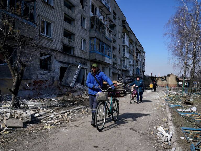 MARIUPOL, UKRAINE - MARCH 21: People walk past damaged buildings as civilians are evacuated along humanitarian corridors from the Ukrainian city of Mariupol under the control of Russian military and pro-Russian separatists, on March 21, 2022. (Photo by Stringer/Anadolu Agency via Getty Images)