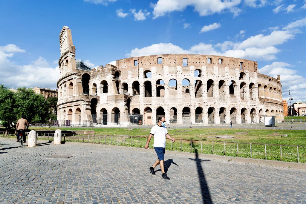 Un hombre con mascarilla camina frente al Coliseo de Roma