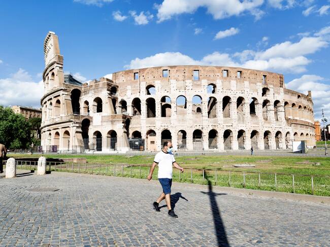 Un hombre con mascarilla camina frente al Coliseo de Roma