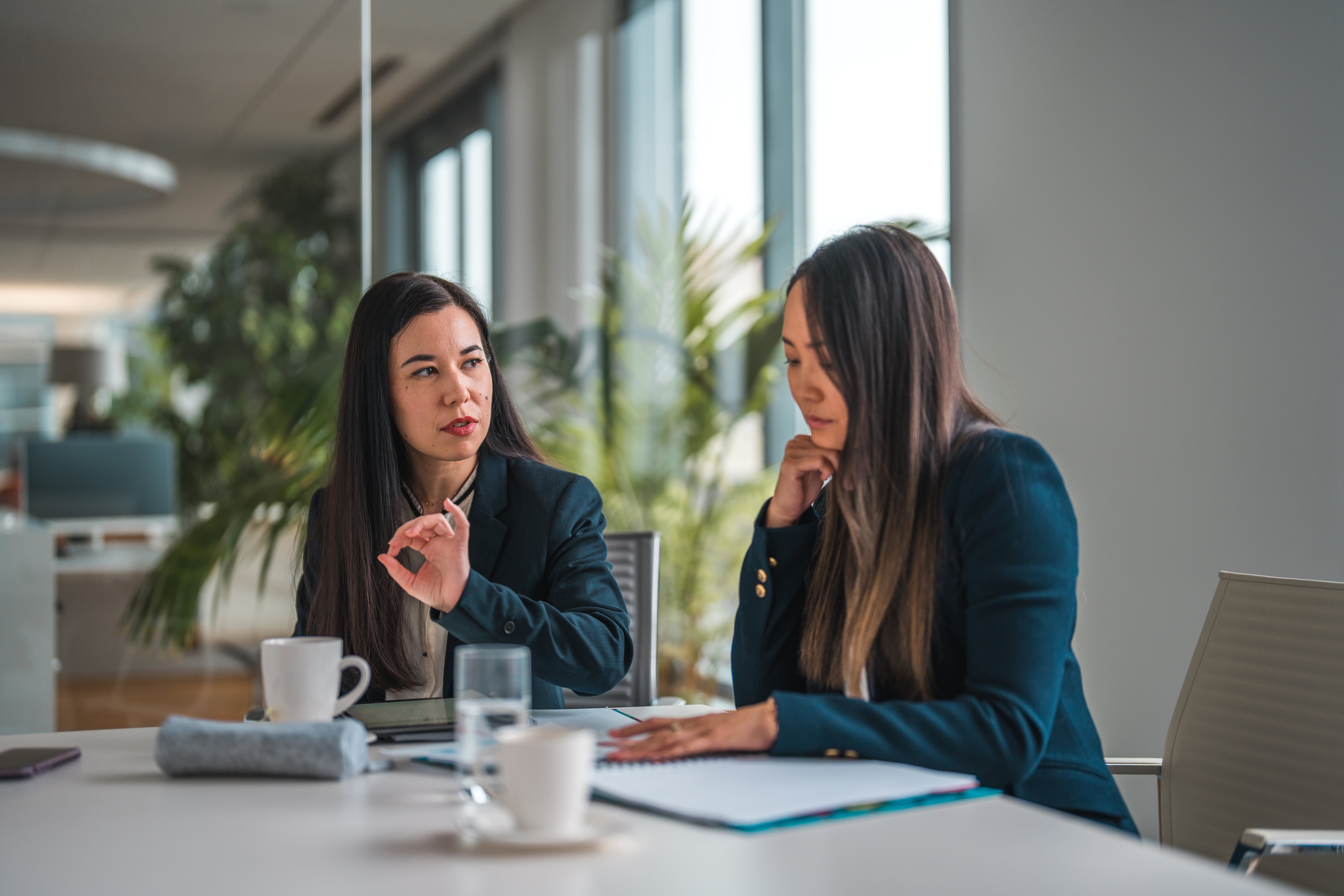 Mid adult female employees working in a financial institution. They are talking and discussing a business strategy.