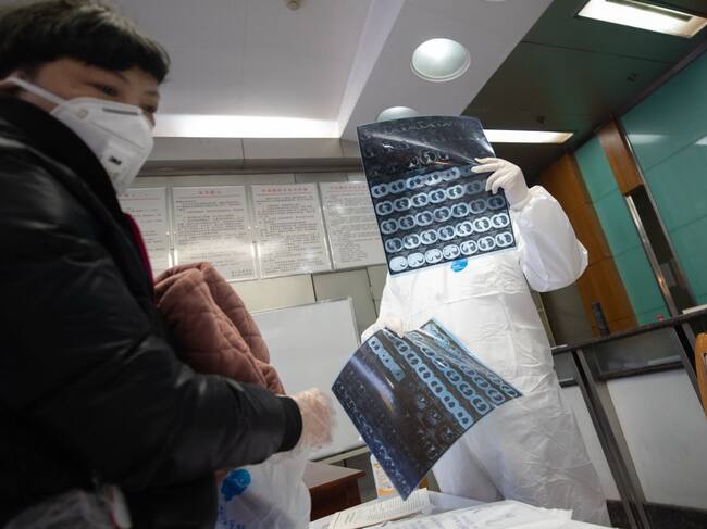 Un médico revisa a una paciente en un centro de aislamiento en China