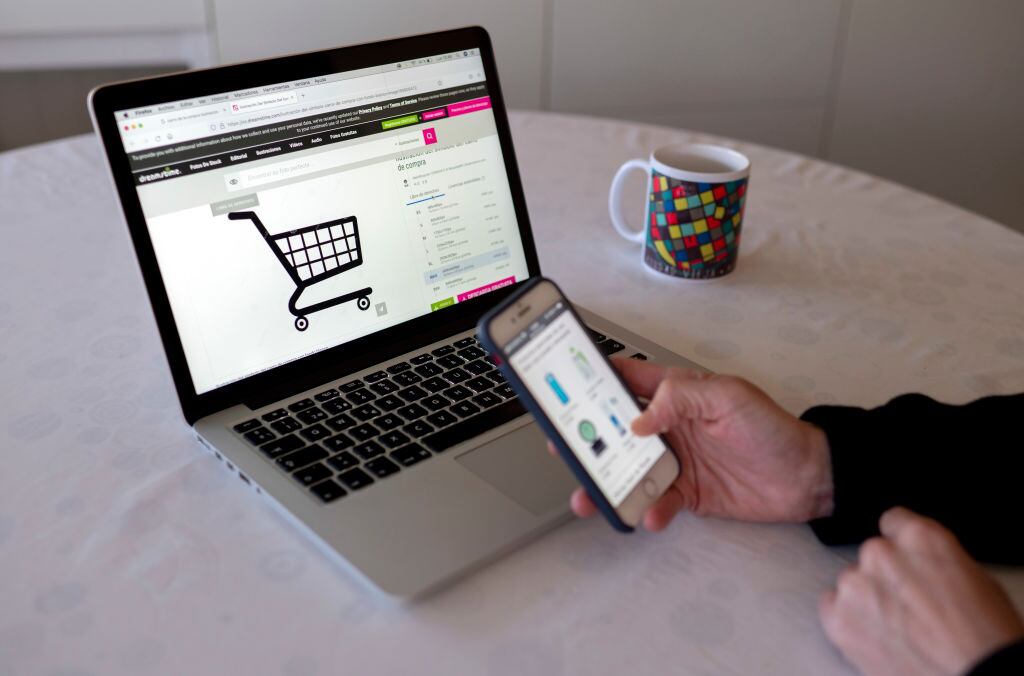 MADRID, SPAIN - JANUARY 03: A person shops with their mobile phone and computer on the day the online sales begin, on January 3, 2022, in Madrid, Spain. The January and February sales season will see a 7.5% increase in hiring, driven by traditional commerce but, above all, by e-commerce, due to new consumer preferences and the uncertainty of the sixth wave of coronavirus. Contracts will increase from 164,055 signed in 2021 to more than 176,000 expected in 2022. (Photo By Alberto Ortega/Europa Press via Getty Images)