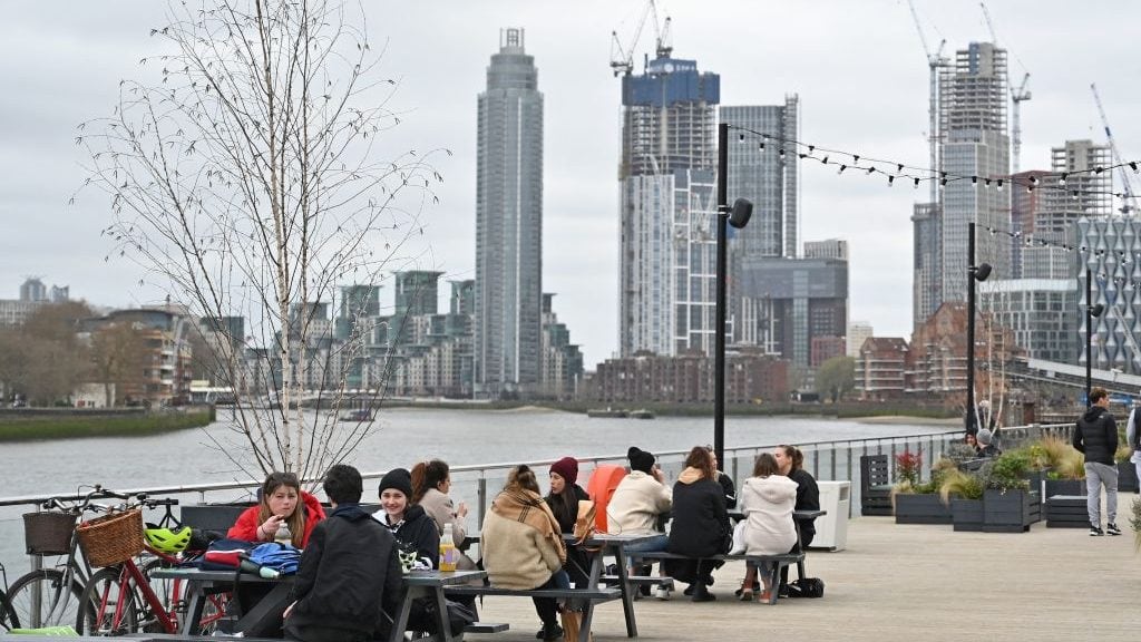 People sit at tables socialising on The Coaling Jetty beside the River Thames in London on March 28, 2021. - From Monday, England's stay-at-home order to combat the spread of the coronavirus will be relaxed to enable groups of up to six people to meet outside. The government plans to allow outdoors drinking in pub gardens, and non-essential retail such as hairdressers, from April 12. (Photo by Justin TALLIS / AFP) (Photo by JUSTIN TALLIS/AFP via Getty Images)