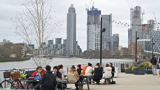 People sit at tables socialising on The Coaling Jetty beside the River Thames in London on March 28, 2021. - From Monday, England's stay-at-home order to combat the spread of the coronavirus will be relaxed to enable groups of up to six people to meet outside. The government plans to allow outdoors drinking in pub gardens, and non-essential retail such as hairdressers, from April 12. (Photo by Justin TALLIS / AFP) (Photo by JUSTIN TALLIS/AFP via Getty Images)