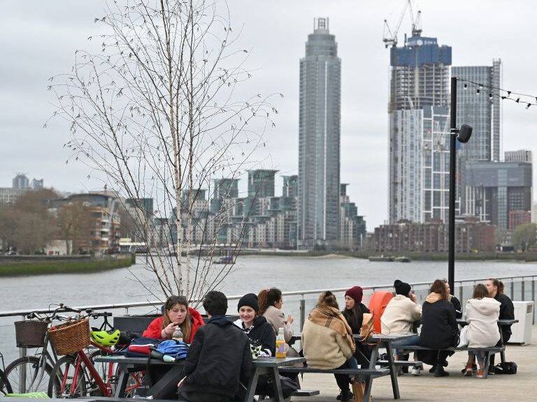 People sit at tables socialising on The Coaling Jetty beside the River Thames in London on March 28, 2021. - From Monday, England's stay-at-home order to combat the spread of the coronavirus will be relaxed to enable groups of up to six people to meet outside. The government plans to allow outdoors drinking in pub gardens, and non-essential retail such as hairdressers, from April 12. (Photo by Justin TALLIS / AFP) (Photo by JUSTIN TALLIS/AFP via Getty Images)