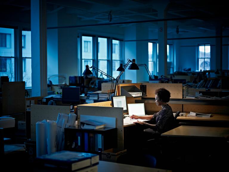 Businesswoman working at desk examining documents in empty office at night