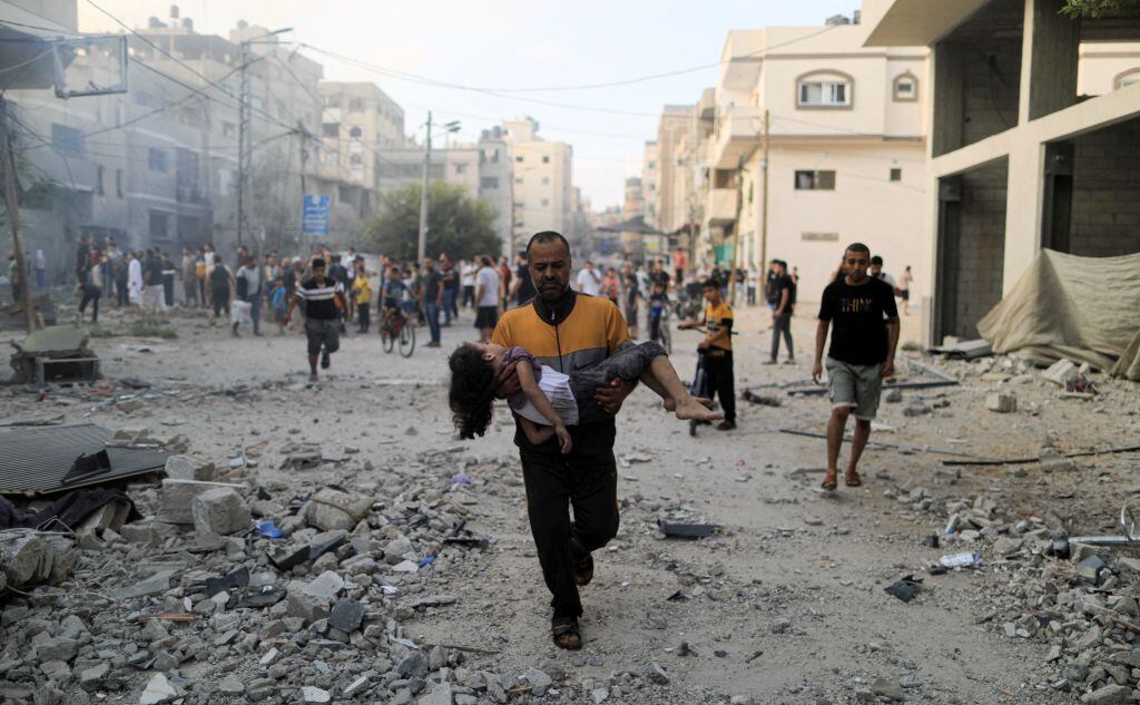 Un palestino lleva una niña herida tras un bombardeo de Israel sobre Gaza