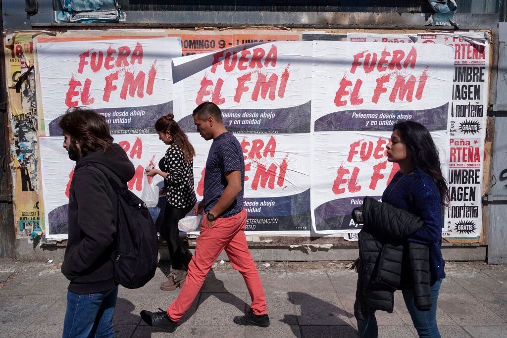 Las personas caminan ante carteles en rechazo al FMI en Buenos Aires en 2018