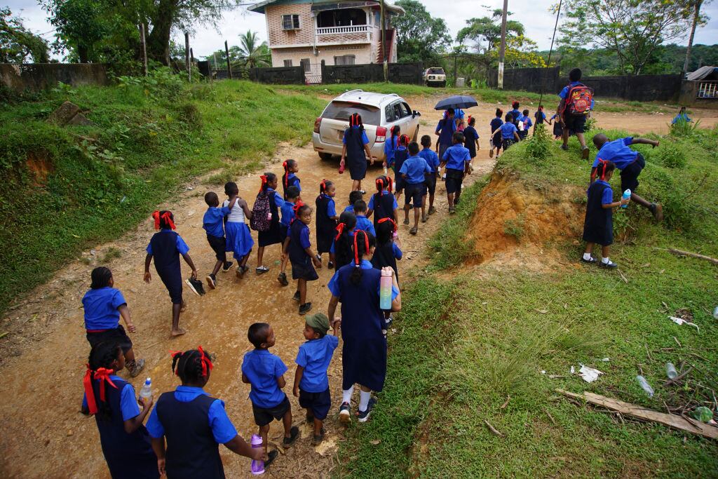 Niños y niñas salen de una escuela en Port Kaituma del Esequibo, zona que actualmente administra Guyana y que busca anexar Venezuela