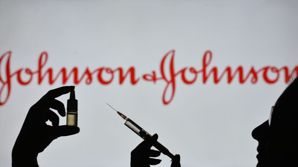 IRELAND - 2021/02/07: In this photo illustration a silhouette of a man holding a medical syringe and a vial seen displayed in front of the Johnson and Johnson logo on a screen. (Photo Illustration by Cezary Kowalski/SOPA Images/LightRocket via Getty Images)