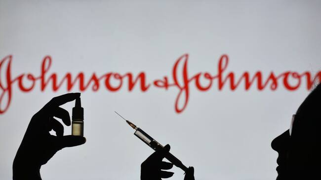 IRELAND - 2021/02/07: In this photo illustration a silhouette of a man holding a medical syringe and a vial seen displayed in front of the Johnson and Johnson logo on a screen. (Photo Illustration by Cezary Kowalski/SOPA Images/LightRocket via Getty Images)