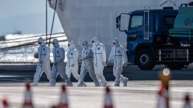 YOKOHAMA, JAPAN - FEBRUARY 11: Emergency workers in protective clothing walk from the Diamond Princess cruise ship as it sits docked at Daikoku Pier where it is being resupplied and newly diagnosed coronavirus cases taken for treatment as it remains in quarantine after a number of the 3,700 people on board were diagnosed with coronavirus, on February 11, 2020 in Yokohama, Japan. 130 passengers are now confirmed to be infected with coronavirus as Japanese authorities continue treating people on board. The new cases bring the total number of infections to 156 in Japan, the largest number outside of China. (Photo by Carl Court/Getty Images)