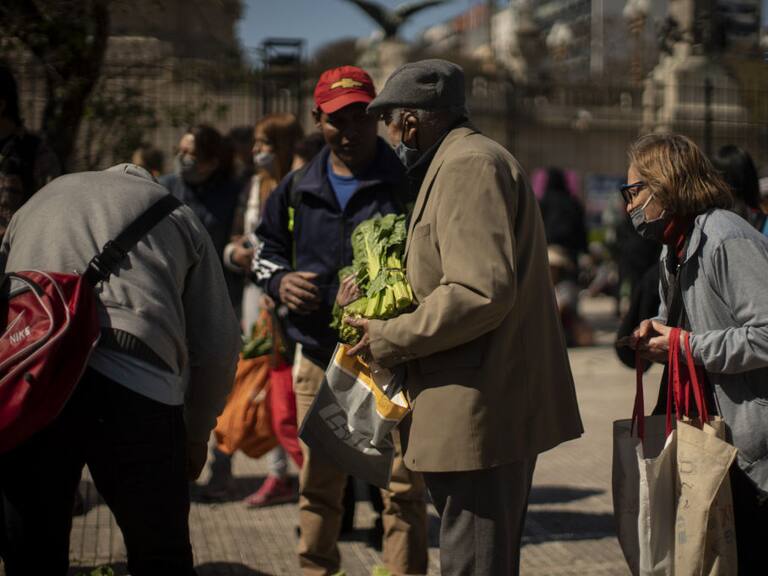 Personas adultas buscan vegetales en una feria en Argentina