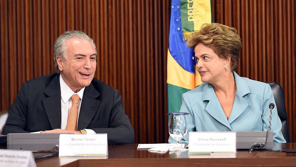 Brazilian President Dilma Rousseff (R) gestures next her Vice President Michel Temer, during a ministerial meeting at the Planalto Palace in Brasilia, on October 8, 2015.  Rousseff claims to detect a glimmer at the end of the tunnel in Brazil's political crisis, but what she really may be seeing, analysts say, are the headlights of an oncoming train. AFP PHOTO/EVARISTO SA        (Photo credit should read EVARISTO SA/AFP via Getty Images)