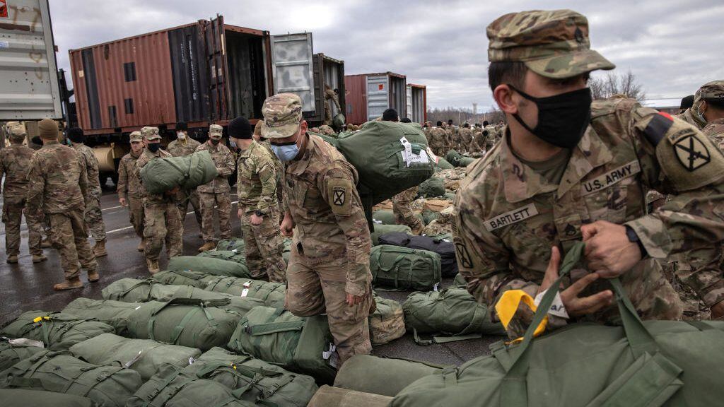 FORT DRUM, NEW YORK - DECEMBER 10: U.S. Army soldiers retrieve their duffel bags after they returned home from a 9-month deployment to Afghanistan on December 10, 2020 at Fort Drum, New York. The 10th Mountain Division soldiers who arrived this week are under orders to isolate with family at home or with fellow troops in barracks, finishing their quarantine just before Christmas. In the waning days of the Trump Administration and after 19 years of war, the U.S. military continues to reduce troop levels in Afghanistan.  (Photo by John Moore/Getty Images)
