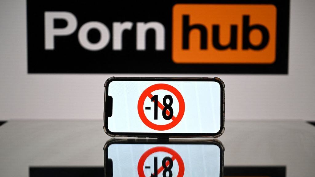 This photograph taken on May 24, 2022 in Toulouse shows screens displaying a minor child sign and the logo of the pornographic site Pornhub. - The judicial examination of Arcom request against porn sites has been postponed to one month, on May 24, 2022. Arcom media regulator requests five pornographic sites to be blocked as they are not preventing the exposure of minors to their content, and French telecom operators to block access to the pornographic sites. (Photo by Lionel BONAVENTURE / AFP) (Photo by LIONEL BONAVENTURE/AFP via Getty Images)