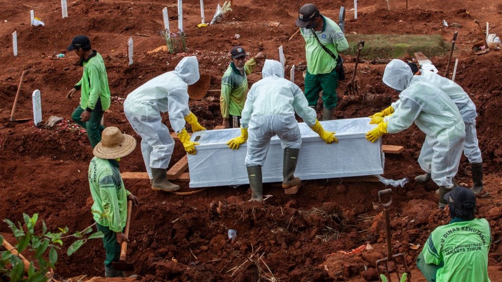 Trabajadores realizan el funeral de una víctima del Covid-19 en Indonesia