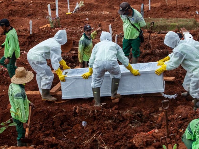 Trabajadores realizan el funeral de una víctima del Covid-19 en Indonesia