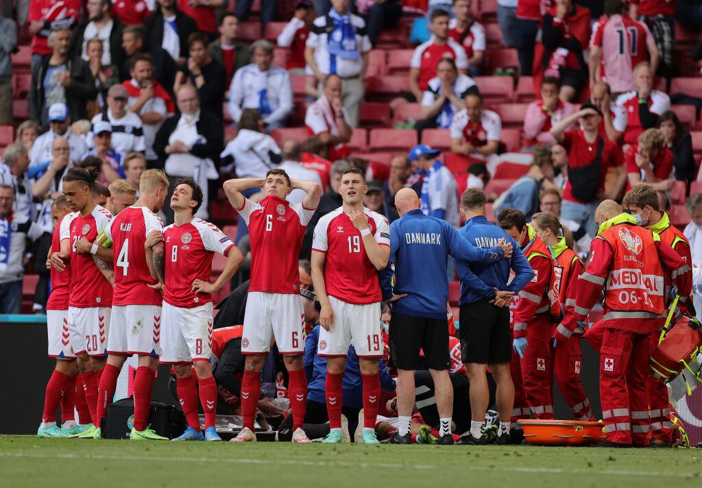 Algunos jugadores de Dinamarca no pueden mirar a Eriksen, claramente afectados. Simon Kjaer contempla el actuar médico con suma tranquilidad. Getty Images.