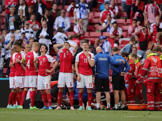 Algunos jugadores de Dinamarca no pueden mirar a Eriksen, claramente afectados. Simon Kjaer contempla el actuar médico con suma tranquilidad. Getty Images.
