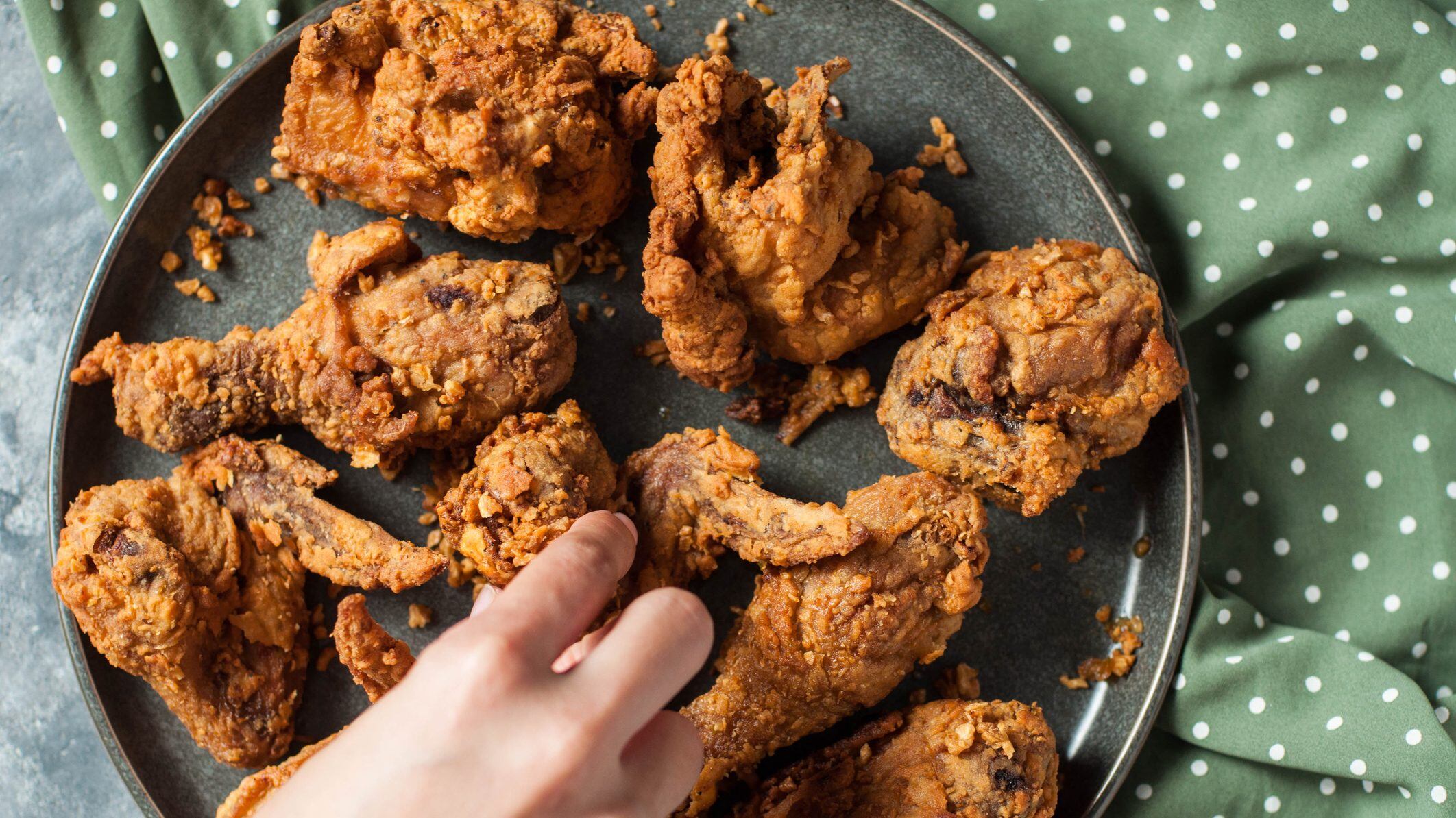 Directly below view of fried garlic butter chicken on a dining table with woman's hand