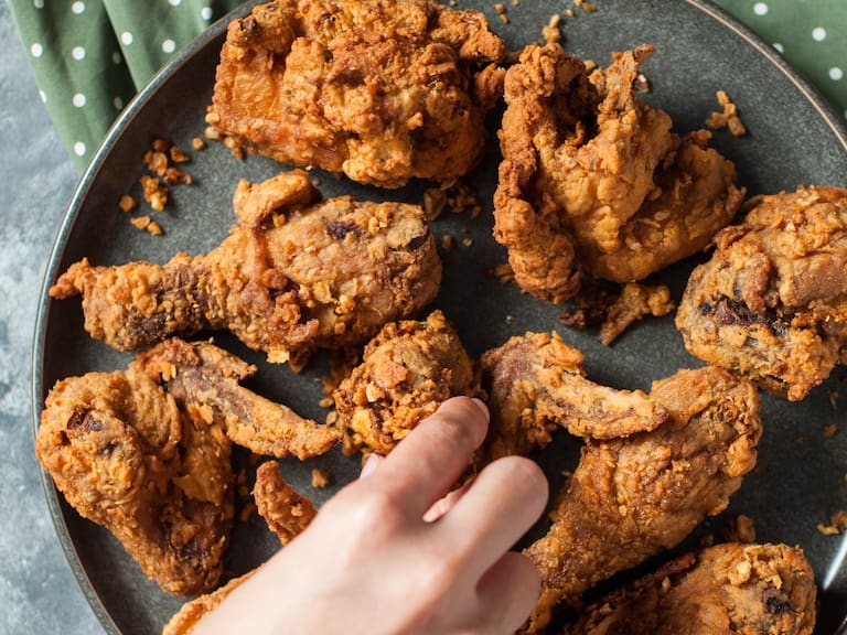 Directly below view of fried garlic butter chicken on a dining table with woman's hand