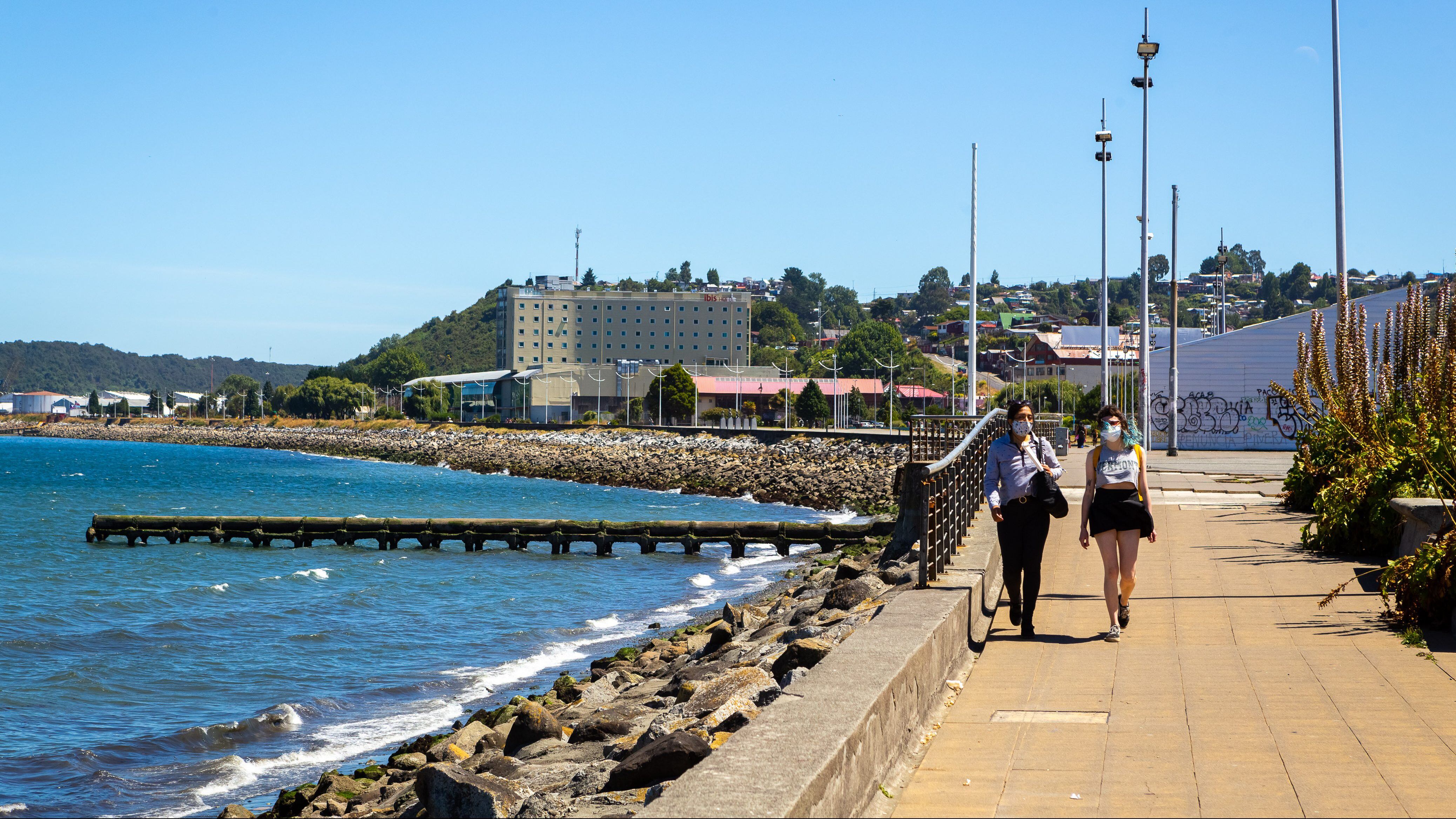 05 de Febrero de 2021 / PUERTO MONTTUna pareja de mujeres con mascarilla caminan por la costanera de la ciudad disfrutando la brisa marina que ofrece el borde costero en un día de verano con inusitadas temperaturas para el sur del país durante cuarentena total vigente por Covid-19 
FOTO: FELIPE CONSTANZO / AGENCIA UNO