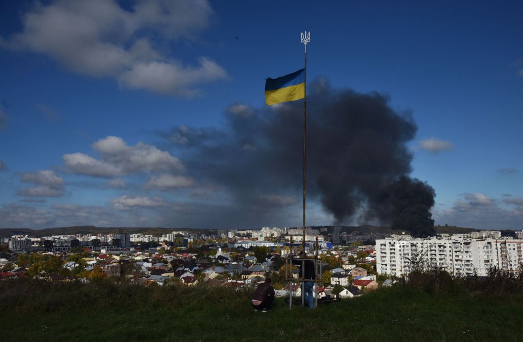 La bandera de Ucrania flamea ante el humo tras el ataque a Leópolis