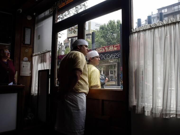 SANTIAGO, CHILE - NOVEMBER 08: Restaurant employees watch the clashes during a protest on November 8, 2019 in Santiago, Chile. Since October 18th, demonstrators demand improvements in health care, the pension system, public education, social mobility and are against the privatization of water services, the rise in public transport fares and government corruption. To contain the protests, President Sebastian Piñera had done reshuffle of cabinet and announced he would raise the minimum salary. (Photo by Claudio Santana/Getty Images)