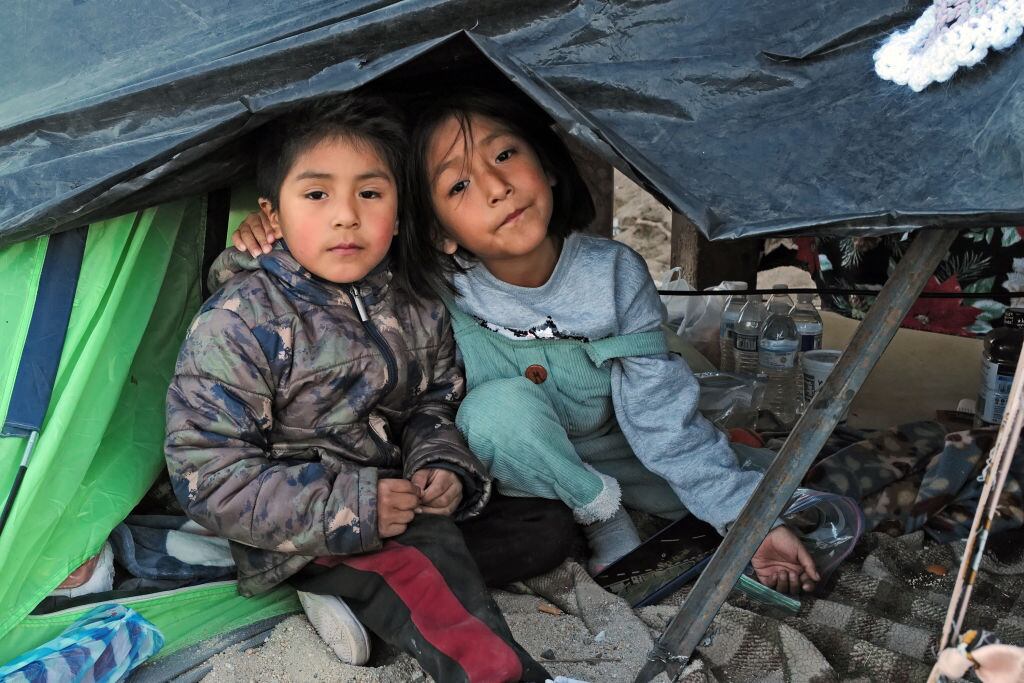 Dos niños migrantes sin compañía en la frontera de México y Estados Unidos, intentando cruzar al estado de California.