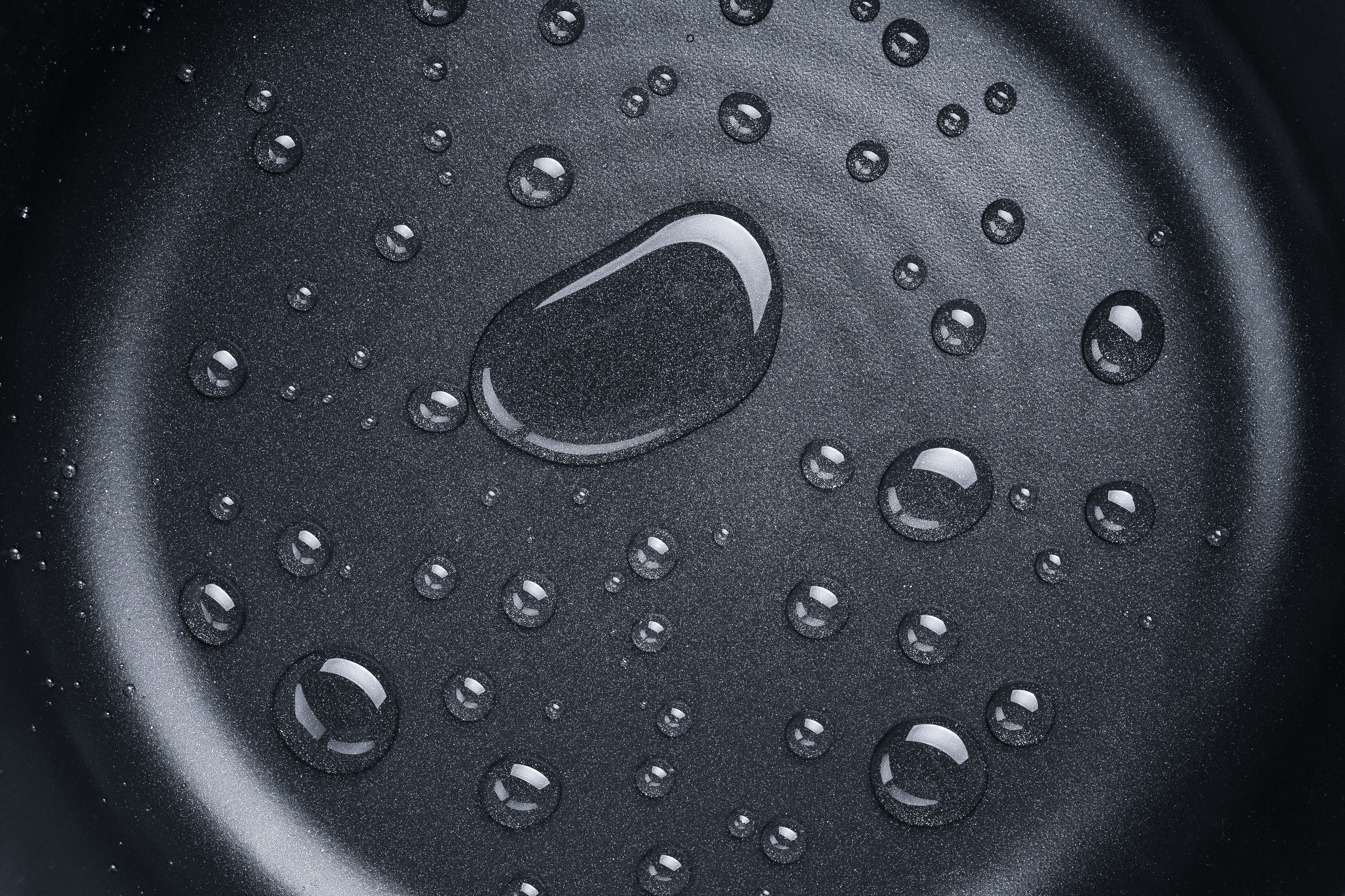A Pattern of Various Shaped Water Drops on A Nonstick Frying Pan Directly Above View.