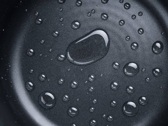 A Pattern of Various Shaped Water Drops on A Nonstick Frying Pan Directly Above View.