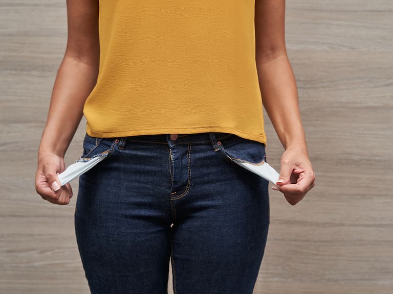 Unrecognizable young women showing her empty pockets without money. Concept of saving money and personal finance.