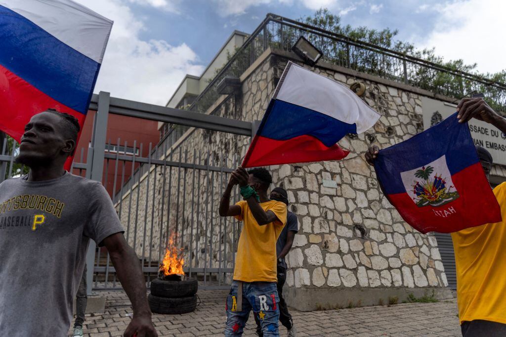 Personas ondean la bandera de Haití frente a la embajada de Canadá