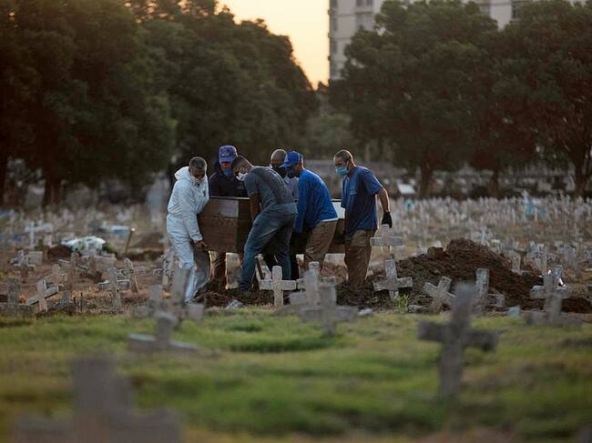 Trabajadores de un cementerio llevan el ataúd de un fallecido por Covid-19 en Brasil