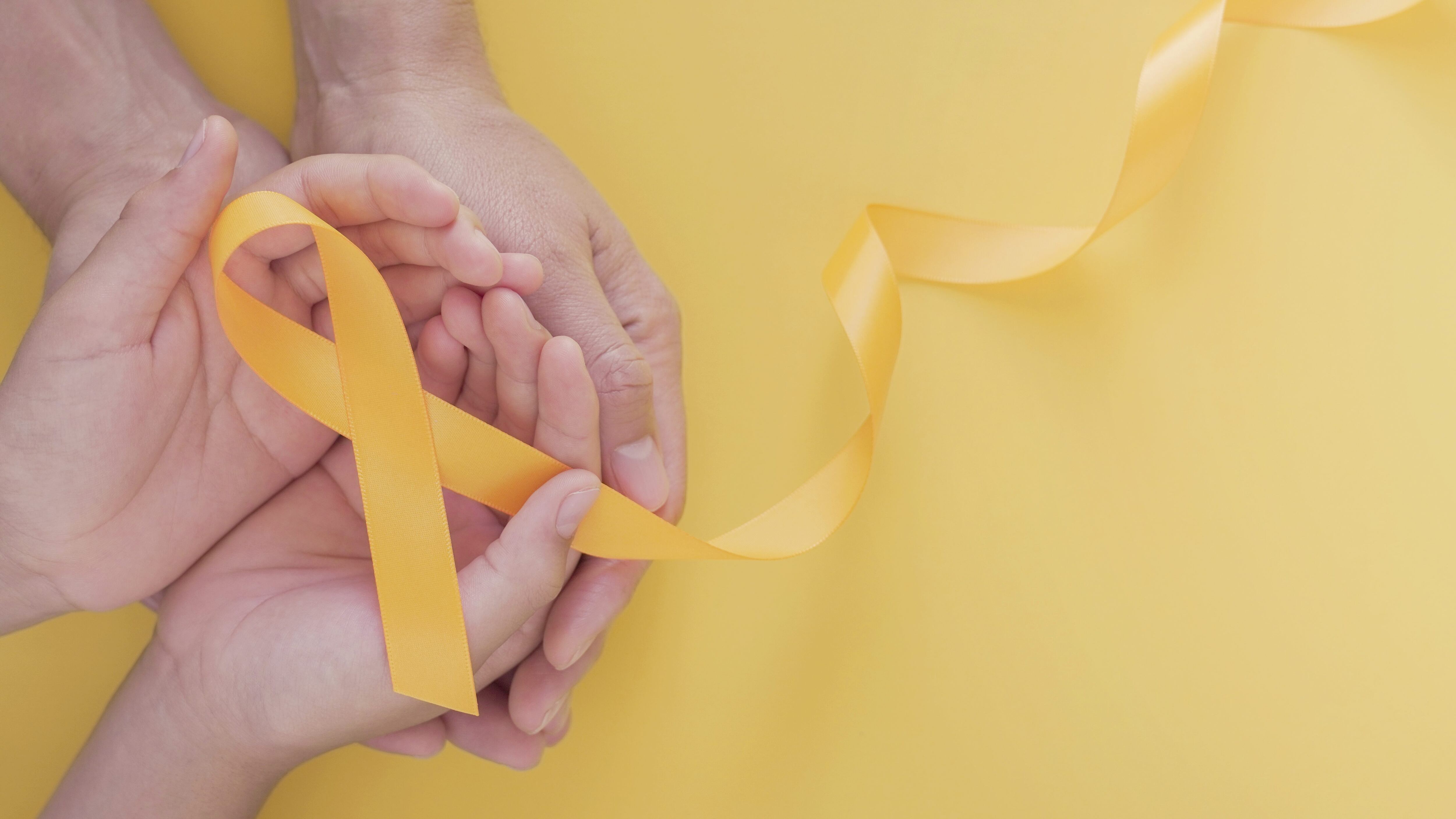 adult and child hands holding yellow gold ribbon, Sarcoma Awareness, Bone cancer, childhood cancer awareness, world suicide prevention day, September Yellow