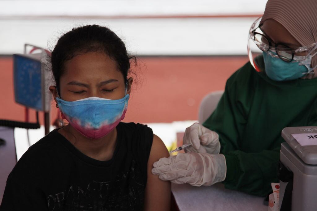 Trabajadora de la salud vacuna a una mujer en Indonesia