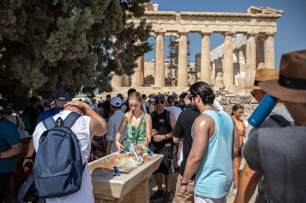 Turistas intentan obtener líquido y captar sombra en la Acrópolis en Grecia