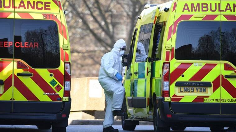 A member of the ambulance service wearing personal protective equipment is seen leading a patient (unseen) into an ambulance at St Thomas' Hospital in London on March 24, 2020. - Britain's leaders on Tuesday urged people to respect an unprecedented countrywide lockdown, saying that following advice to stay at home would stop people dying of coronavirus. (Photo by Daniel LEAL / AFP) (Photo by DANIEL LEAL/AFP via Getty Images)